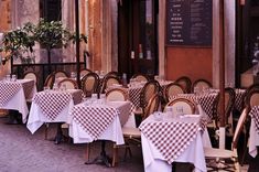 tables and chairs are set up outside in front of a restaurant with checkered tablecloths