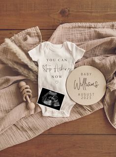 a baby's bodysuit and photo are laying on the floor next to a blanket