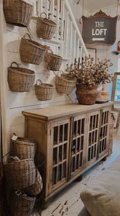 baskets are hanging on the wall next to a wooden cabinet with doors and drawers underneath