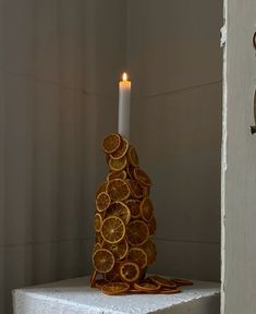 a candle that is sitting on some kind of shelf with orange slices in front of it