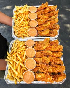 two trays filled with fried chicken and french fries next to dipping sauces on the side