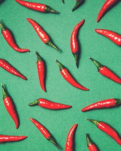 many red peppers are scattered on a green surface