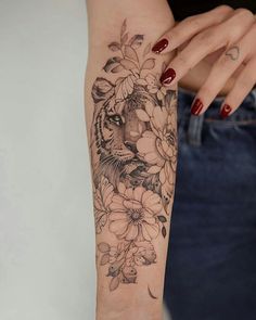 a woman's arm with flowers and a tiger tattoo on the left side of her arm