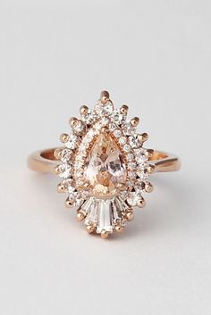 an engagement ring with a pear shaped diamond surrounded by small white and light brown diamonds