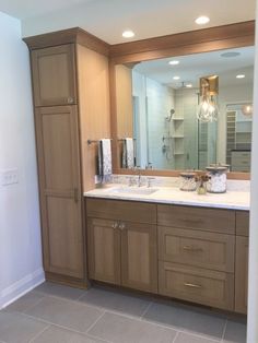 a large bathroom with two sinks and cabinets in it's center area, along with a walk - in shower