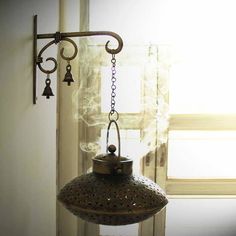 an old fashioned wind chime hanging in front of a window with the sun shining through