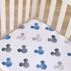 a white crib with blue and gray mickey mouse sheets on it's sides