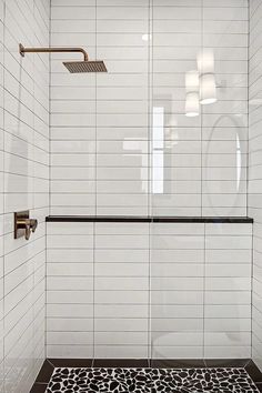 a white tiled shower with black and white patterned floor