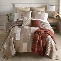 a bed covered in brown and white plaid comforter next to a night stand with a lamp on it