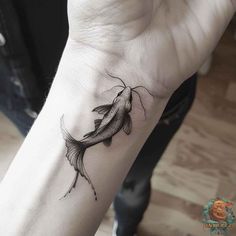 a small black and white fish tattoo on the wrist