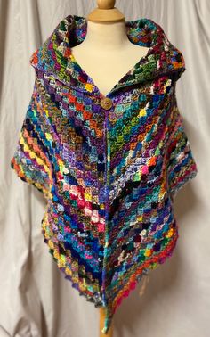 a colorful crocheted shawl on a mannequin