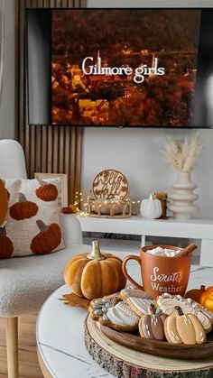 a table topped with cookies and cupcakes on top of a white table next to a tv