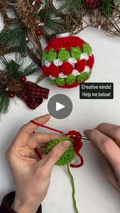 someone crocheting a christmas ornament with red and white balls on it