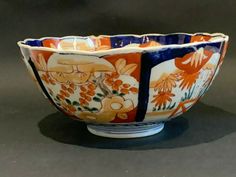 an orange and blue flowered bowl on a black surface with white trim around the edge