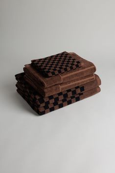 four towels stacked on top of each other in the shape of checkered squares, one brown and one black