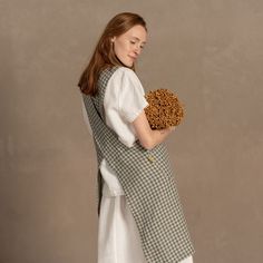 a woman in white dress holding a brown and white basket filled with dried food items