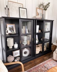 a black bookcase with glass doors and pictures on top