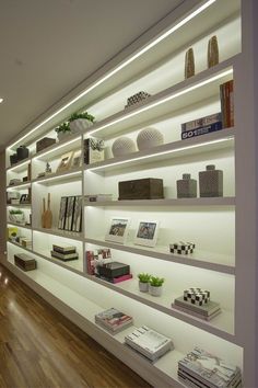 a room filled with lots of books and vases on top of white shelving