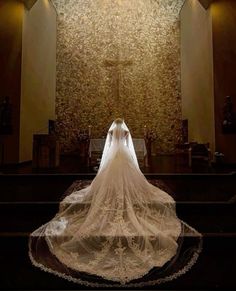 the back of a bride's wedding dress as she stands in front of an alter