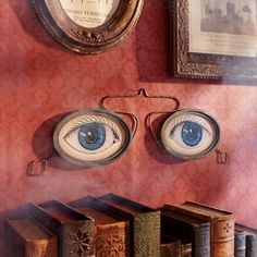 an eyeball on the wall next to some books and a framed picture above it