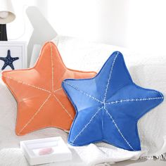 two star shaped pillows sitting on top of a bed next to a white box with a blue and orange star