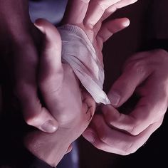 two hands with bandages on them holding something in one hand and another hand wrapped around the other