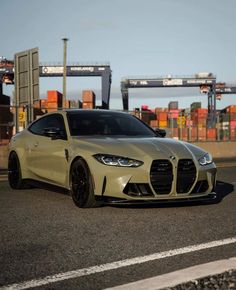 a white sports car is parked on the side of the road in front of shipping containers