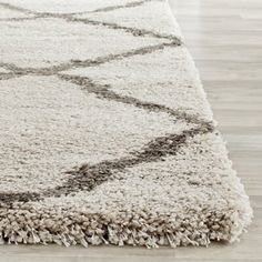 a white rug with black and grey designs on the bottom, sitting on a hard wood floor