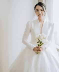 a woman in a white wedding dress holding a bouquet