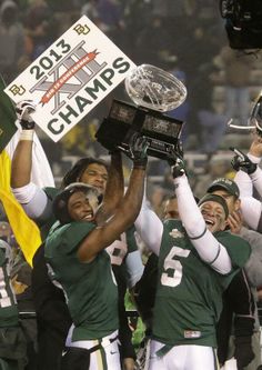 the football players are holding up their trophy and celebrating with each other in front of an audience