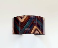 "This unique copper bracelet is made by painting patterns onto copper with a torch, and as the copper heats and cools it turns different colors naturally! Its quite an amazing process. The cuff is 1\" wide and is flexible enough so that you can make it fit your wrist. It is protected with a sealant to keep it from further oxidizing. These are custom made per order, so please keep in mind that with this process, nature is in charge of the colors, so see each one that I make is unique and cannot b Handmade Brown Copper Bangle, Handmade Copper Bangle In Brown, Brown Copper Cuff Bracelet As Gift, Artistic Copper Cuff Bracelet, Artistic Copper Cuff Bracelet Bangle, Artistic Copper Cuff Bangle Bracelet, Brown Copper Bracelet With Patina, Brown Copper Patina Bracelets, Unique Brown Bracelet With Patina