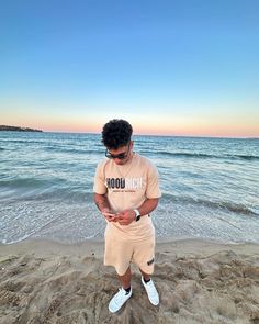 a man standing on the beach looking at his cell phone