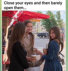 three girls are standing outside talking to each other and one girl is holding a cup