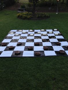 a giant checkerboard board with cupcakes on it in the middle of a yard