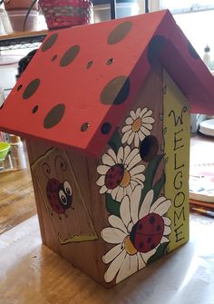 a wooden birdhouse with ladybugs painted on it's side and the roof