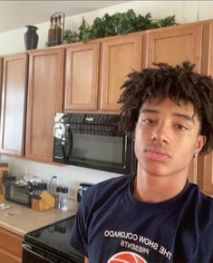 a young man standing in front of a stove top oven next to a kitchen counter