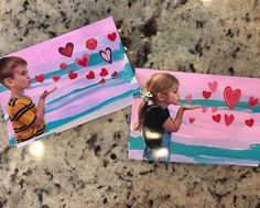 two children's valentine cards with hearts painted on them, sitting on a marble countertop