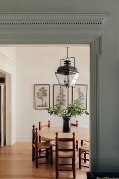 a dining room table and chairs with pictures on the wall behind it in an open doorway