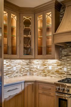 a kitchen with wooden cabinets and stainless steel stove top oven in the center, surrounded by glass front cabinets