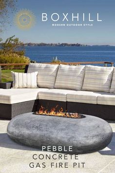 a fire pit sitting on top of a patio next to a couch and table with pillows