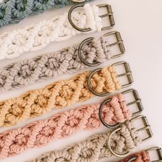 crochet key fobs are lined up on a white surface with metal clips