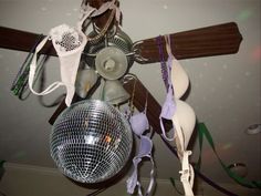 a mirror ball hanging from the ceiling next to other items on a wooden rack and fan