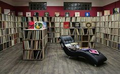 a room filled with lots of books next to a black chair and bookcases