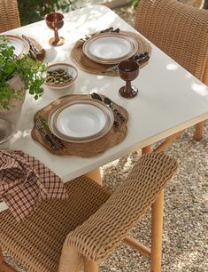 the table is set with plates, silverware and a potted plant on it