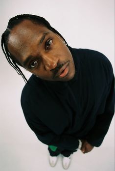 a man with dreadlocks and a black shirt is looking up at the camera