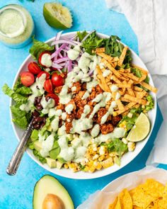 a bowl filled with salad next to an avocado and some other food items