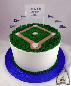 a birthday cake with grass and flags on the top is decorated like a baseball field