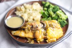 a plate topped with chicken, broccoli and mashed potatoes next to gravy