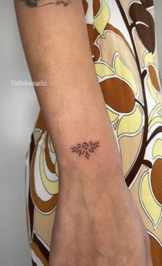 a woman's arm with a small tattoo on the left side of her wrist