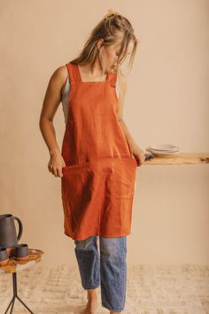 a woman in an orange dress is standing near a table with a plate on it